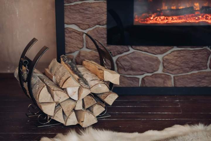 decorative metallic holder with heap wooden logs stony fireplace with burning logs